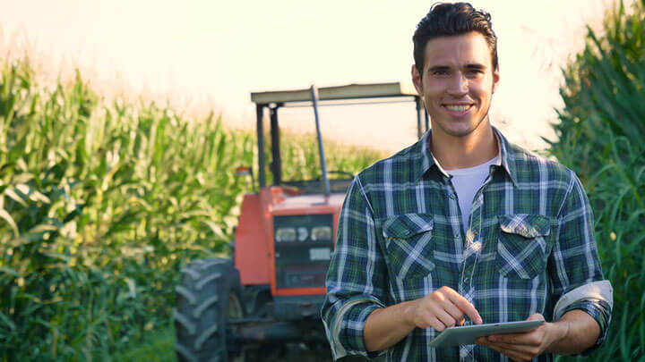 young farmer working in the field with a tractor working in a tablet