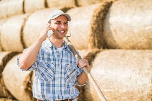 Smiling farmer talking on the phone while in the field